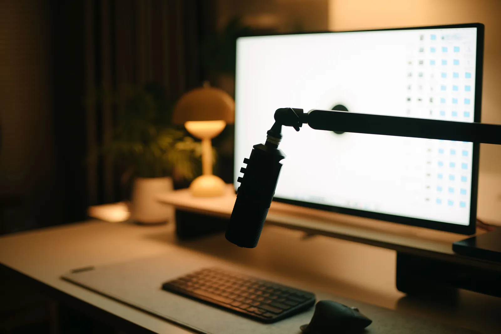 A warm and inviting workspace featuring a computer, microphone, and ambient lighting