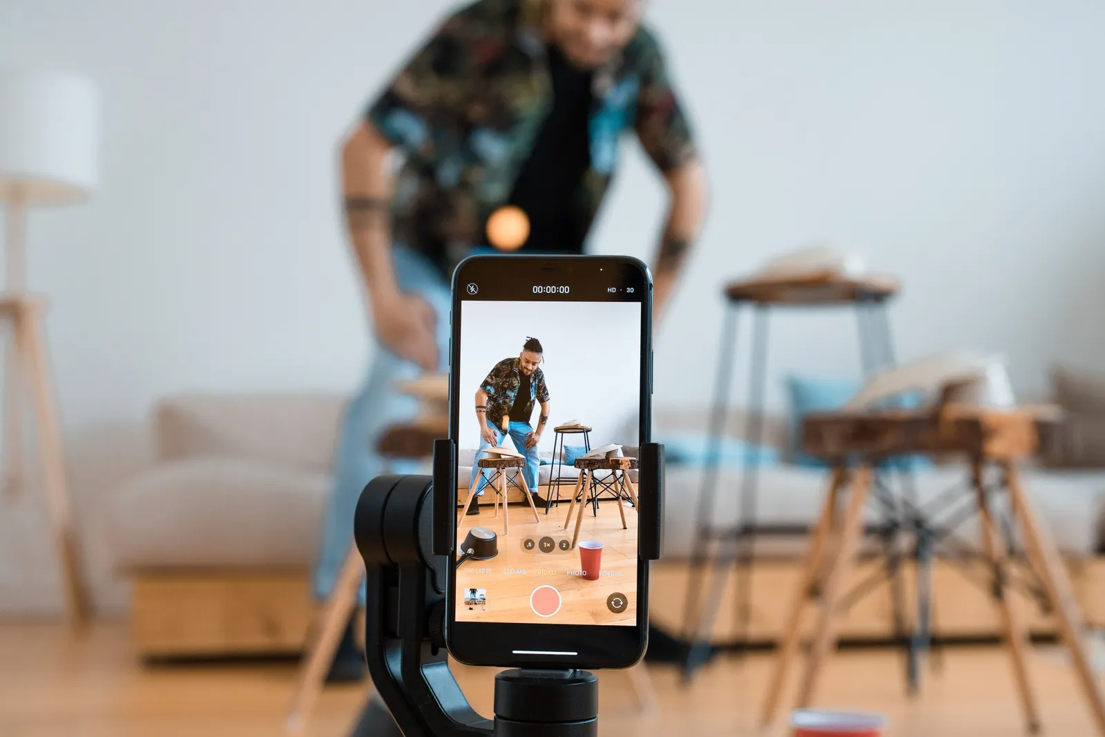 Man recording video content with smartphone on a tripod in a cozy living room