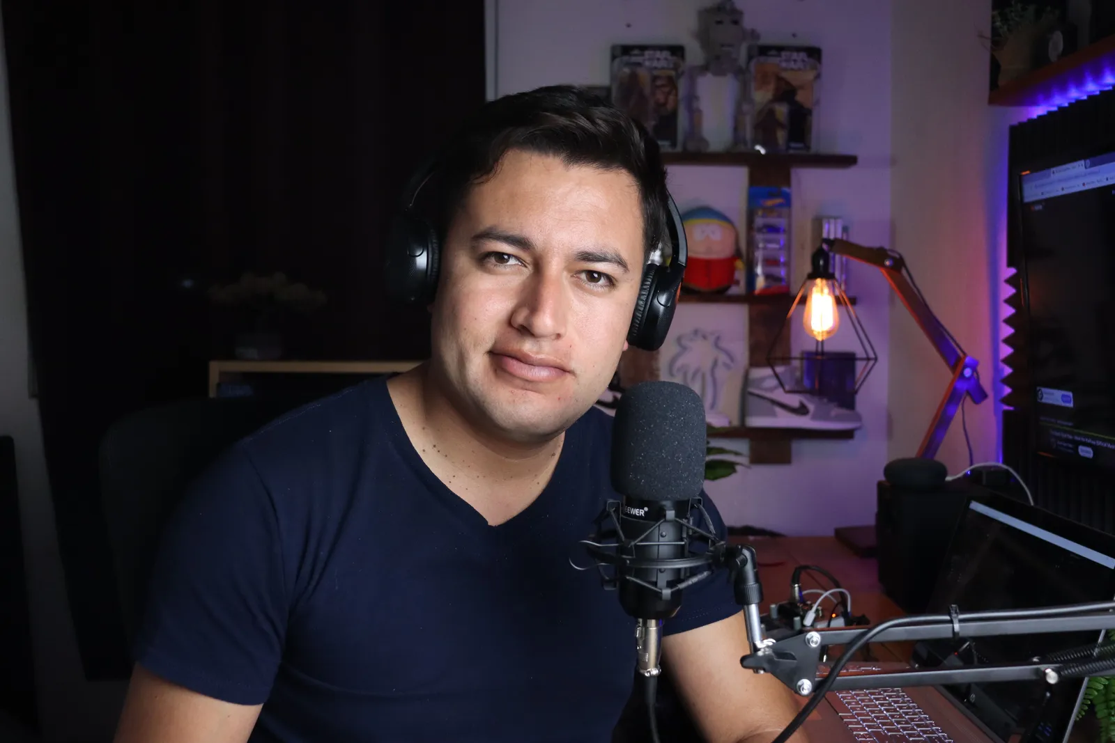 Portrait of a male podcaster in a home studio with microphone and headphones