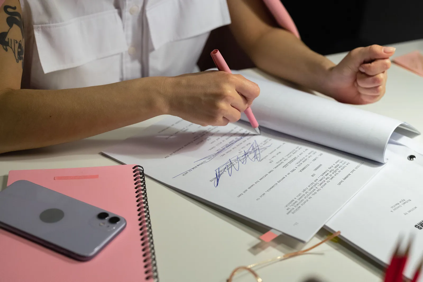 Close-up of a person writing on documents at a well-organized office desk