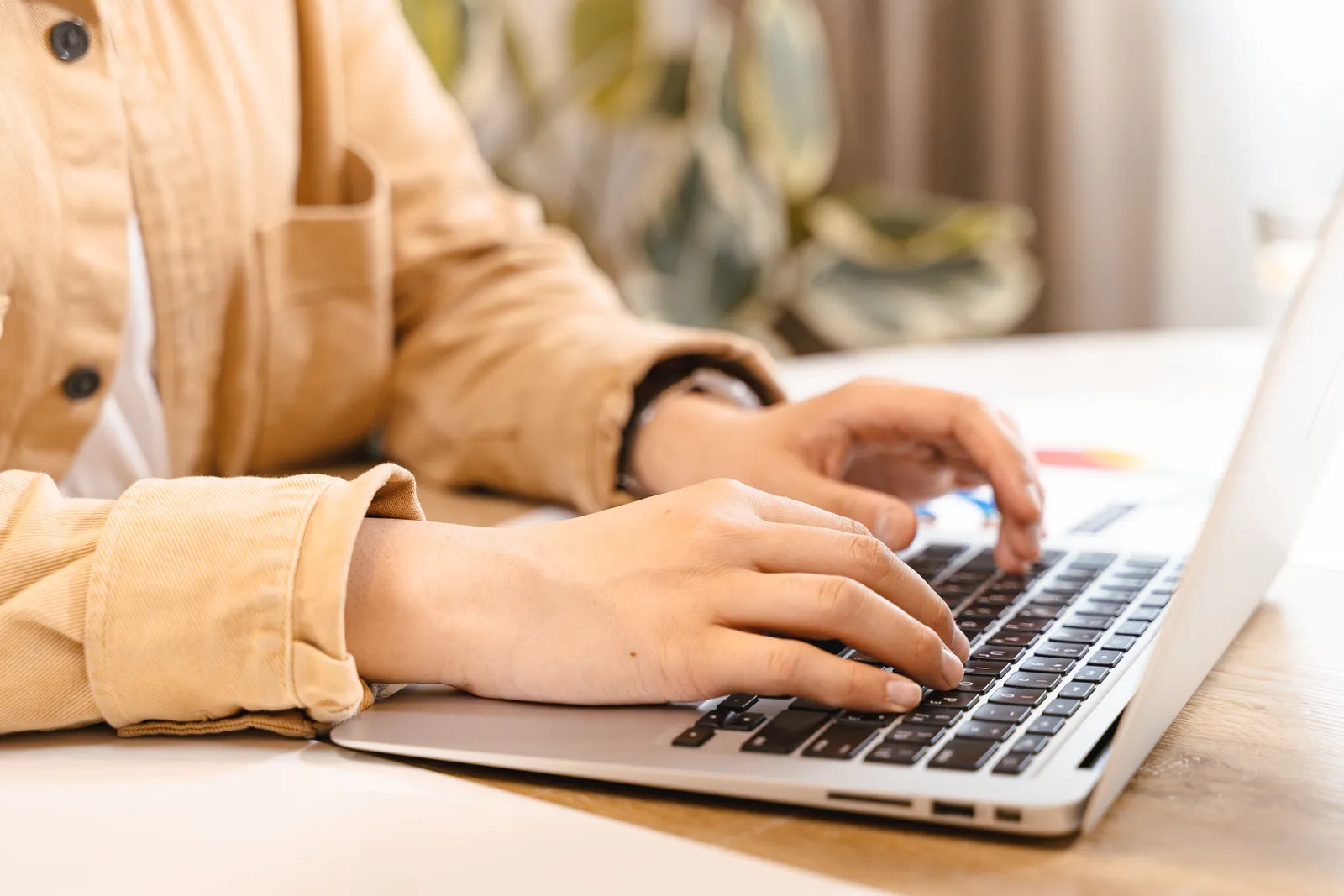 Close-up of hands typing on a laptop in a bright indoor setting, emphasizing work and technology