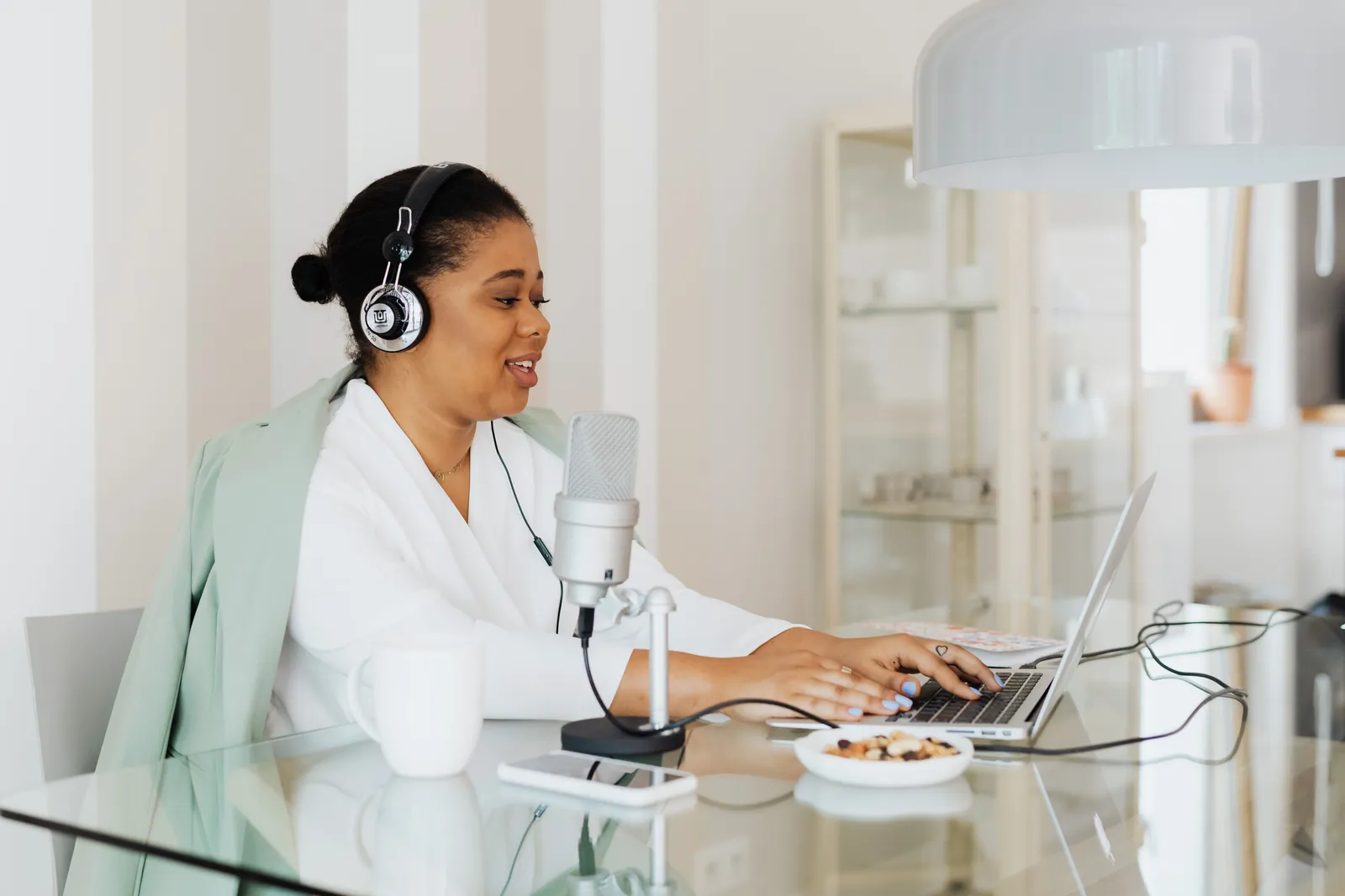Woman podcasting with microphone and laptop in a contemporary office setting