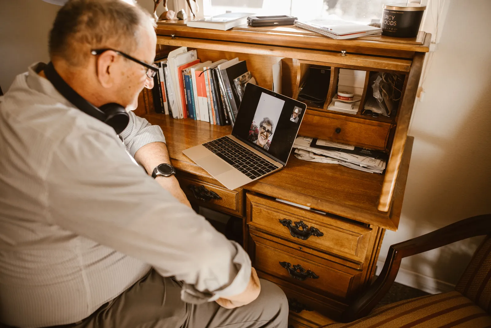 Senior man having a video call using a laptop at a wooden desk indoors