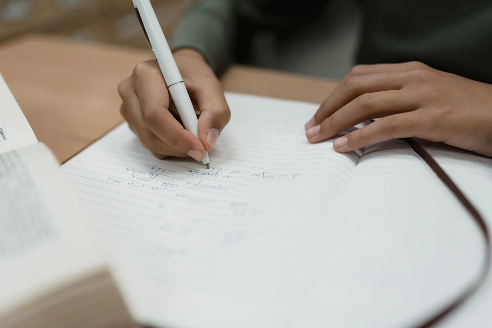 Hands writing notes in an open notebook, focused close-up shot