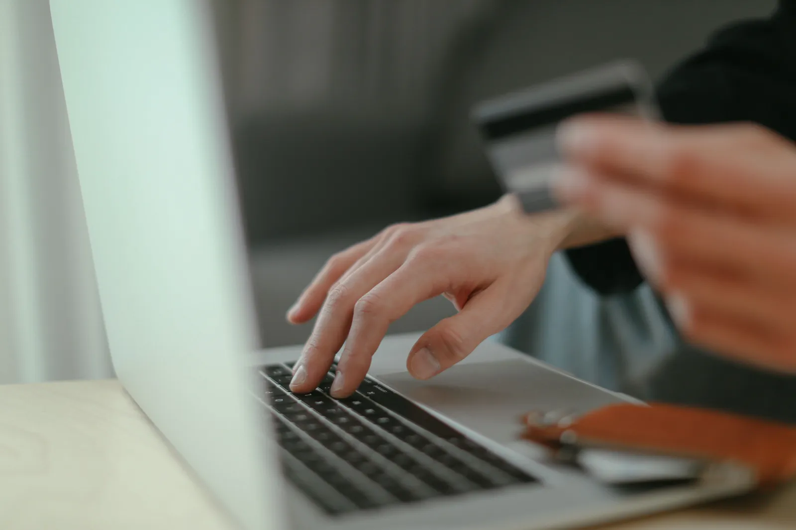 Close-up of hands holding a credit card and typing on a laptop keyboard for online shopping