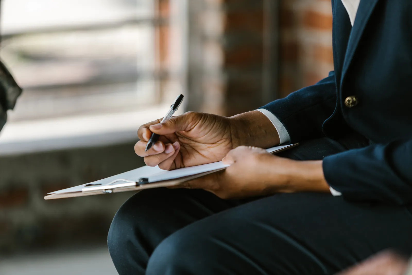 Close-up of a professional writing on clipboard indoors. Ideal for business themes