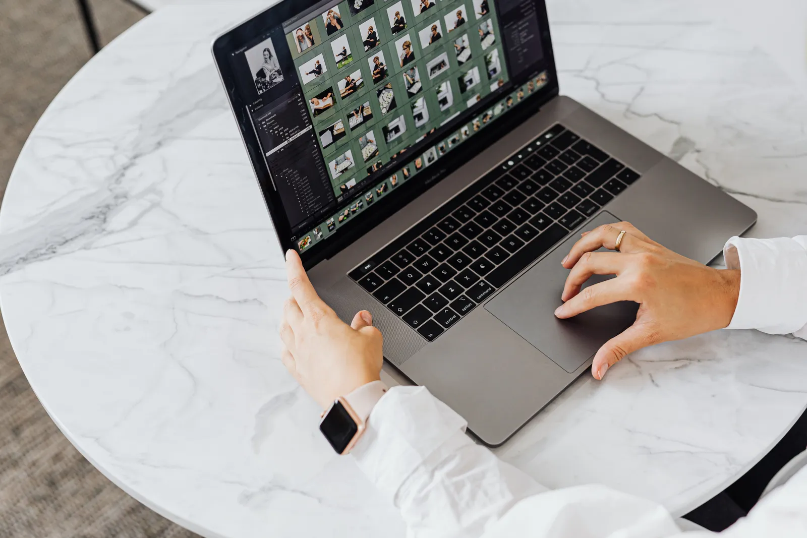 Hands editing photos on laptop, modern workspace on marble table
