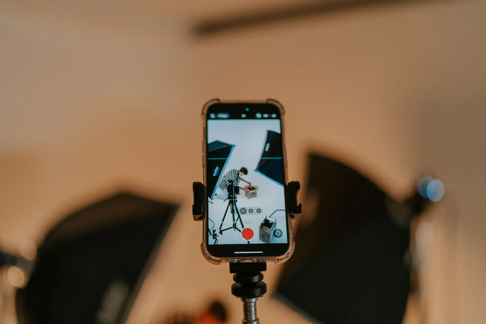 Close-up of a smartphone on a tripod capturing a photo shoot in a studio setting