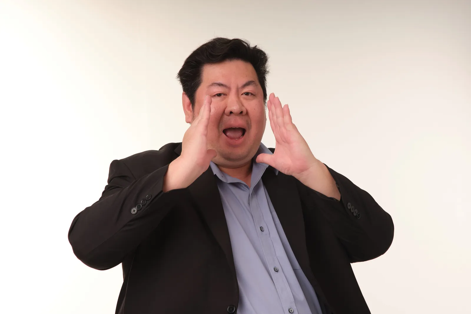 Adult man shouting with hands around mouth in a studio setting