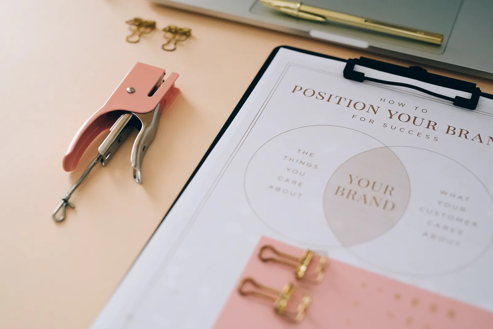 Pink stapler and branding document on a desk showcasing stylish office setup
