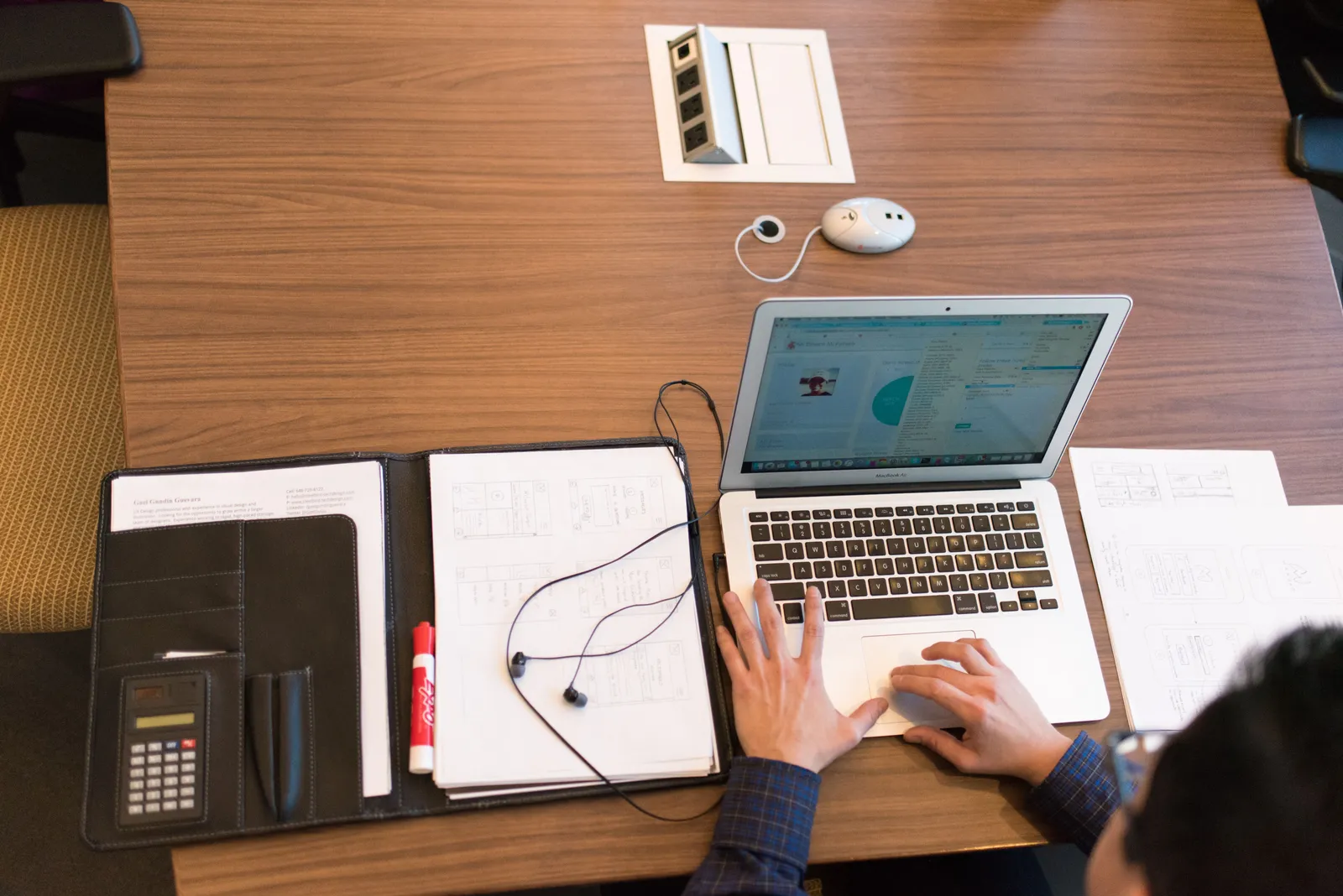 Overhead view of a person working remotely with a laptop and documents on a wooden desk