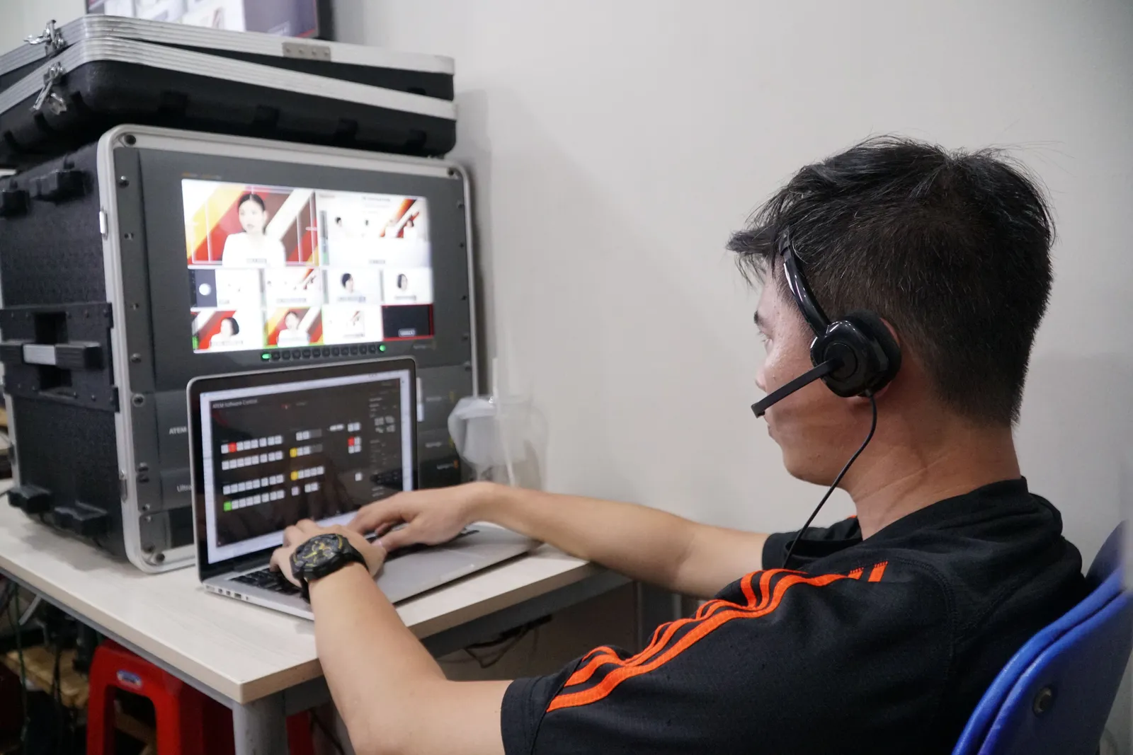 Technician manages multiple video feeds using laptop and monitor in studio setting