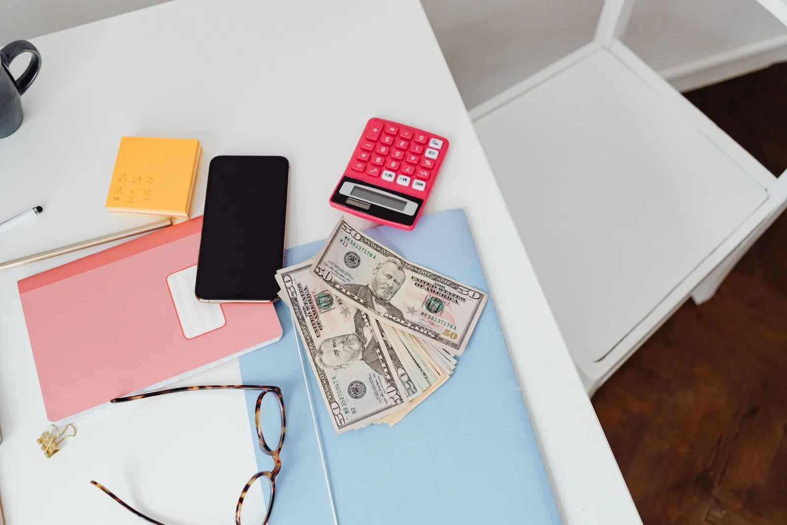 Overhead view of office desk with calculator, money, and glasses, depicting finance and budgeting