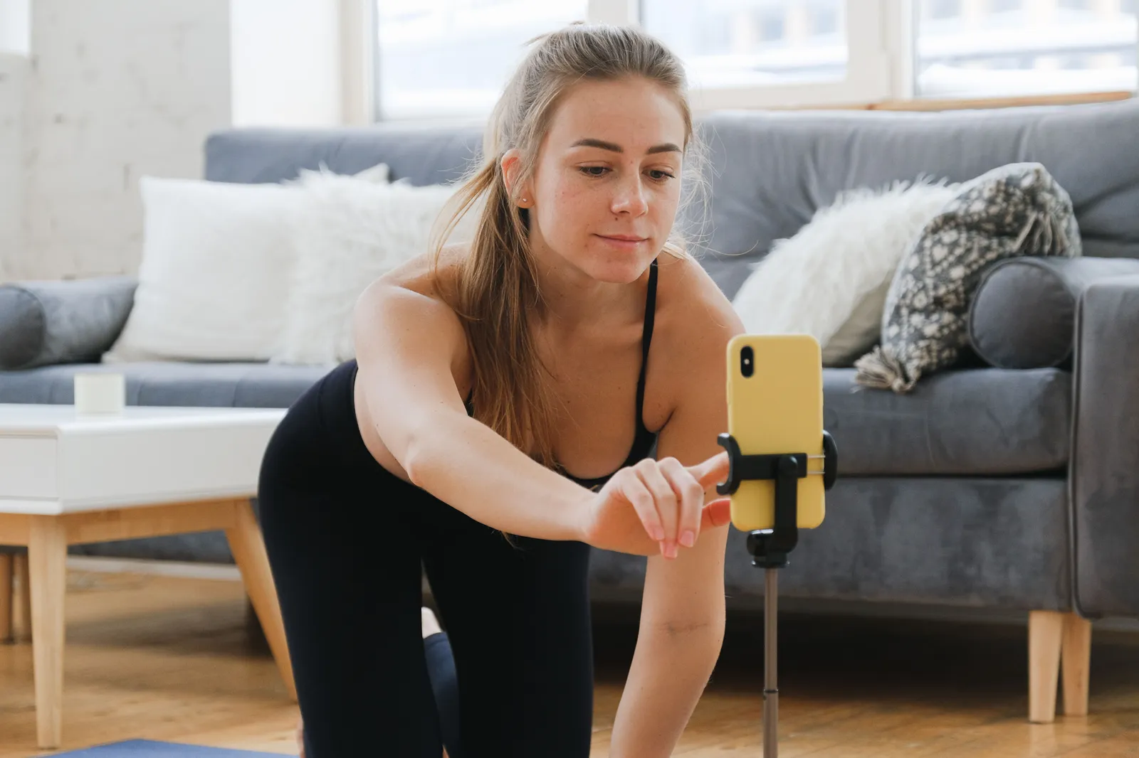 Young woman in activewear vlogging her yoga practice at home using a smartphone on a tripod