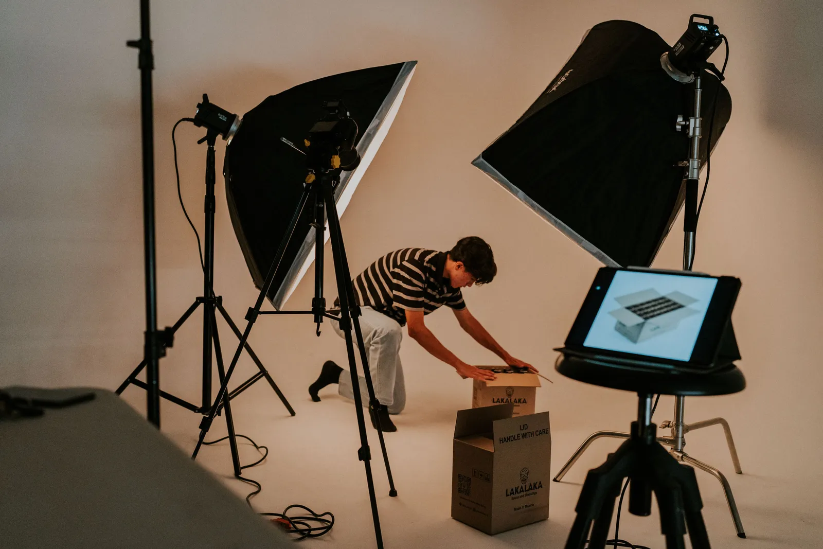 A professional studio scene with a man preparing packages under studio lighting, showcasing a modern photography setup