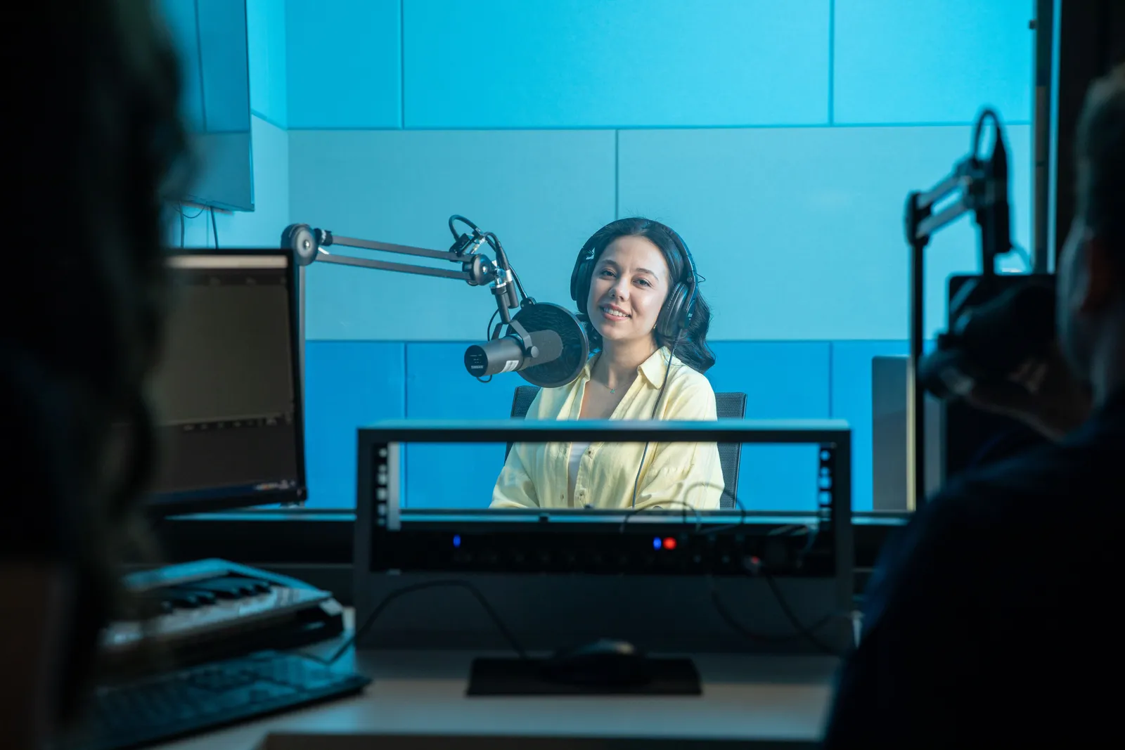 A podcast host records a show in a professional radio studio with microphones and headphones
