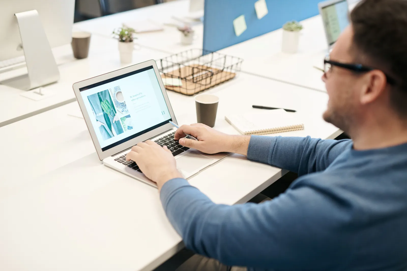 Adult man in office setting working on laptop computer, focused on screen