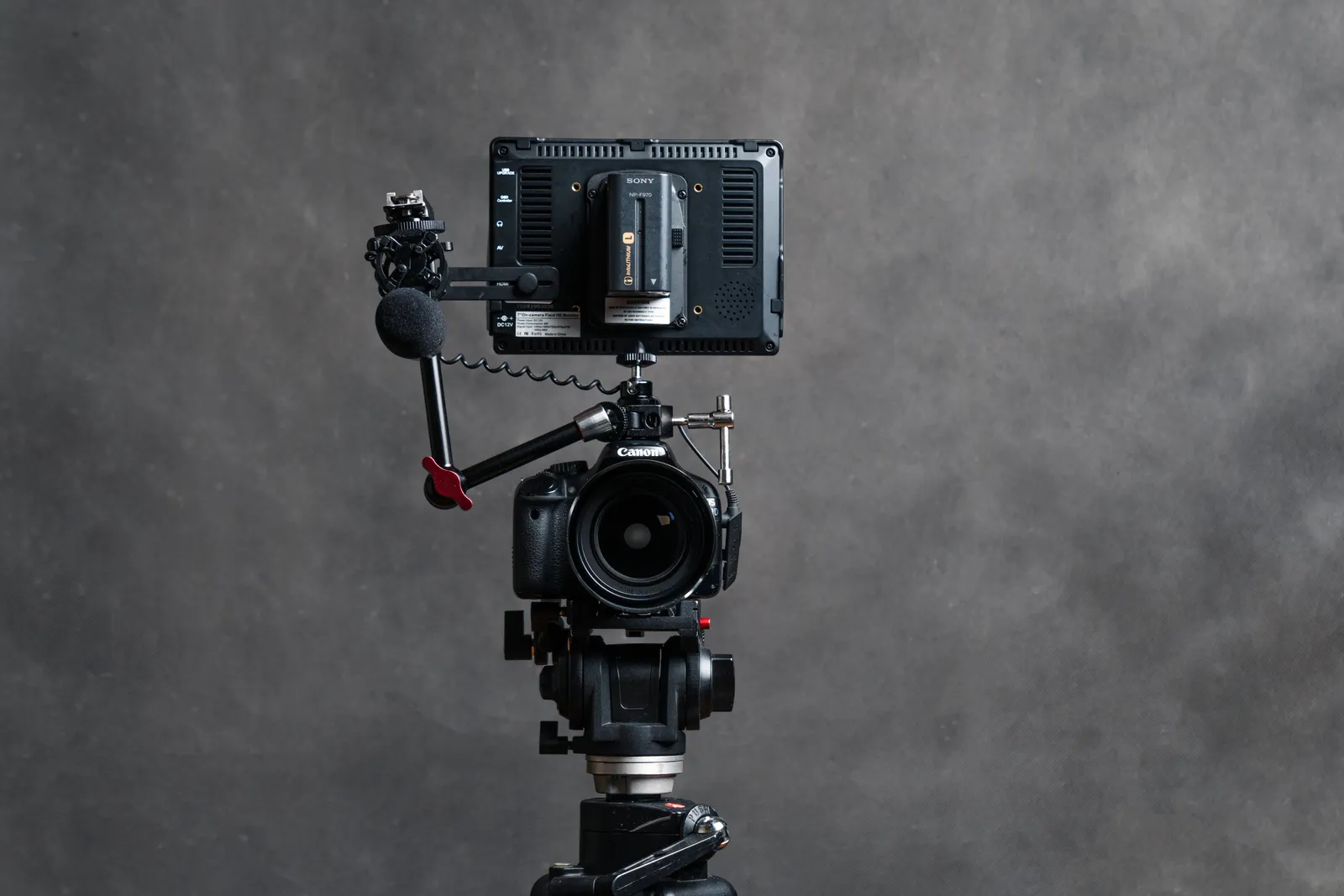 Professional DSLR camera with accessories including microphone and monitor in a studio setting