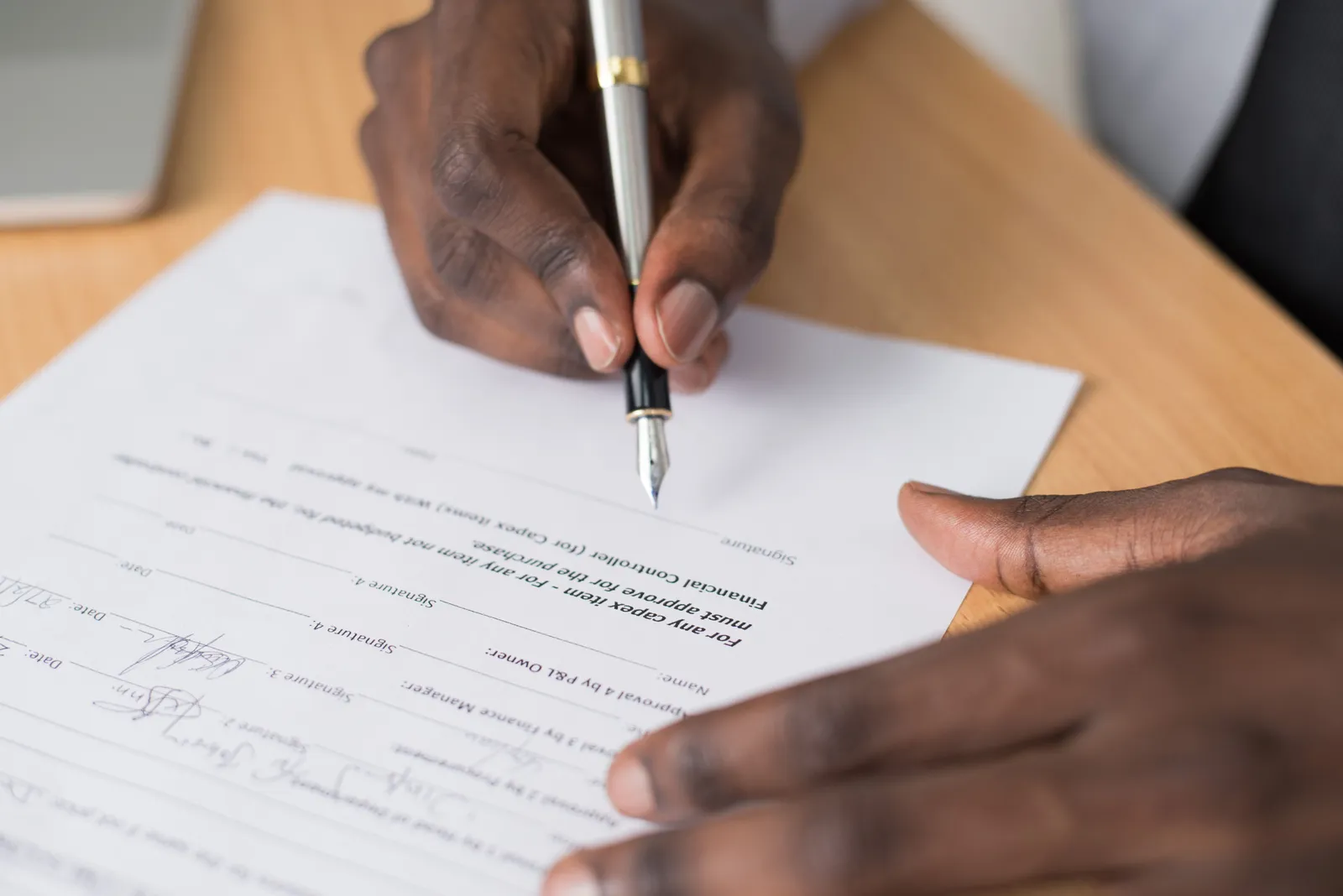 Close-up of a man's hands signing a formal document indoors