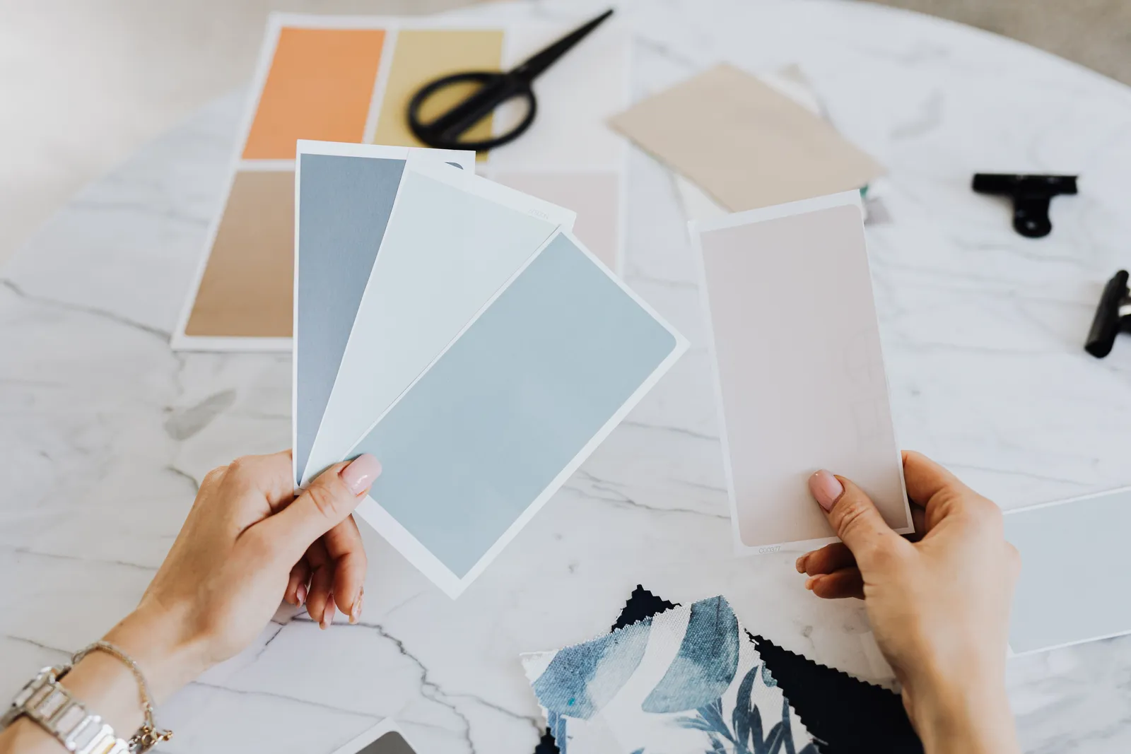 Hands holding color swatches and fabric samples for creative design projects