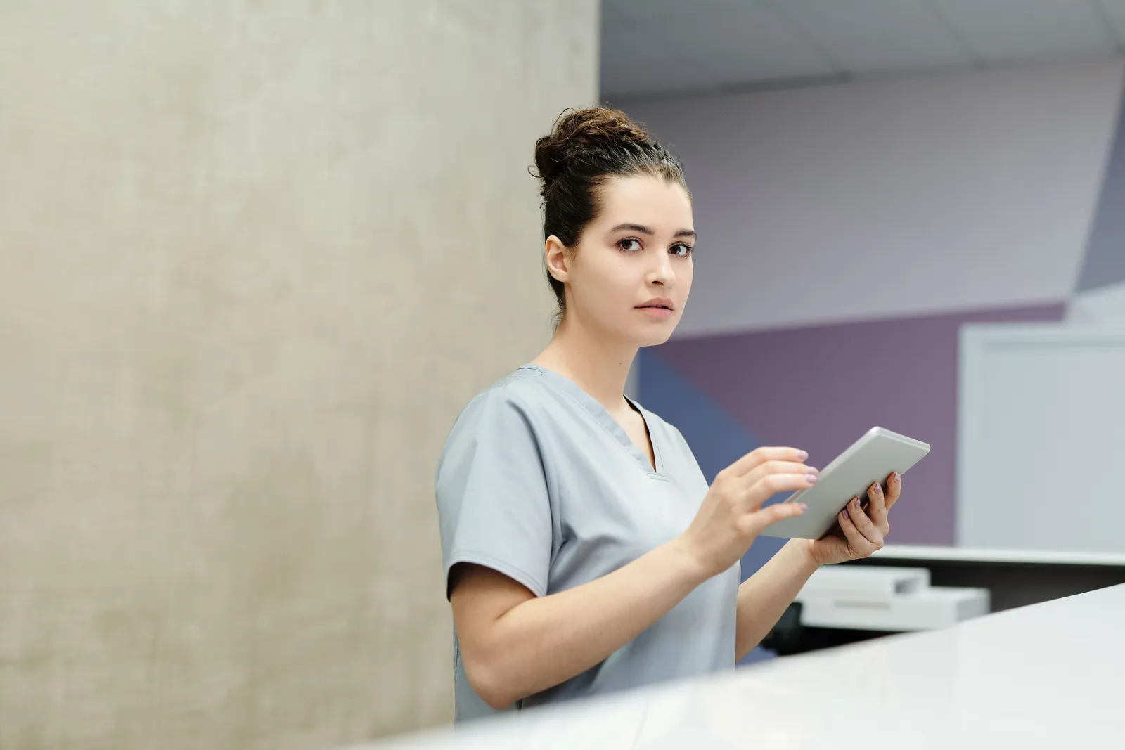 Professional receptionist using a tablet device at a modern office reception desk