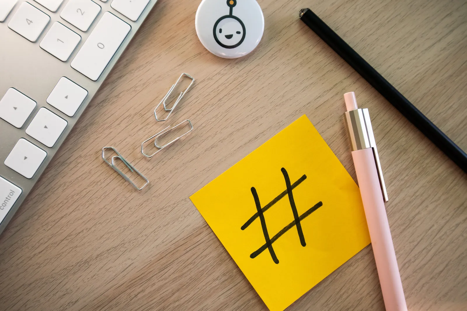 Top view of a modern desk with a hashtag sticky note, keyboard, and stationery items