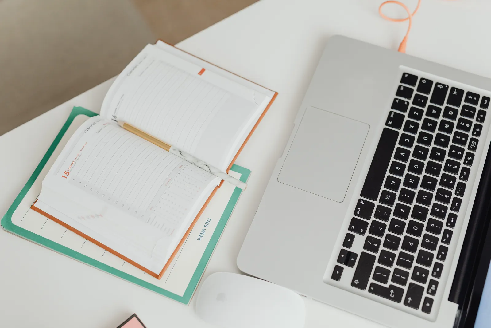 Top view of a clean workspace with a laptop, notebook, and mouse on a desk