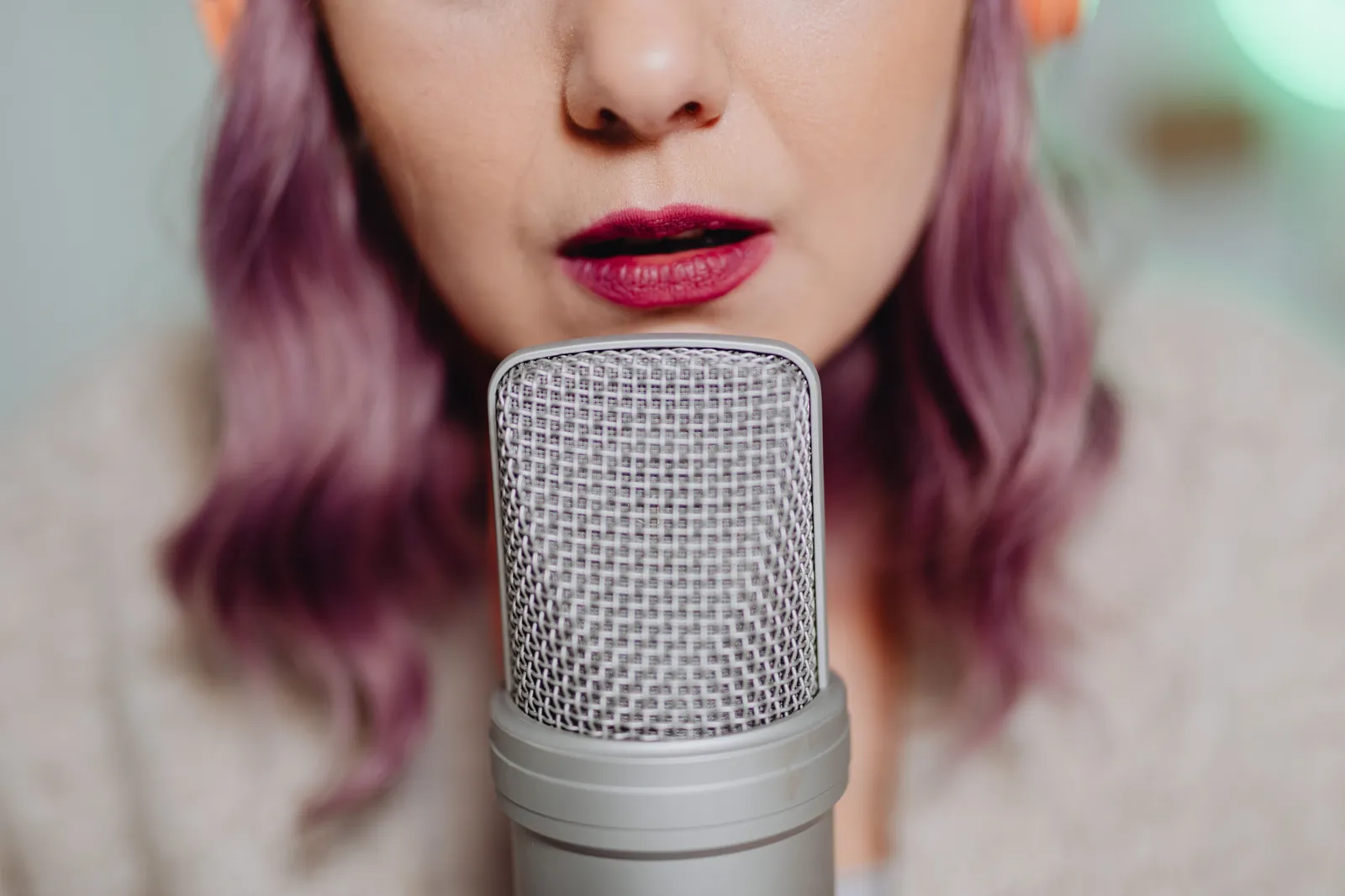 Close-up of a woman with purple hair speaking into a microphone