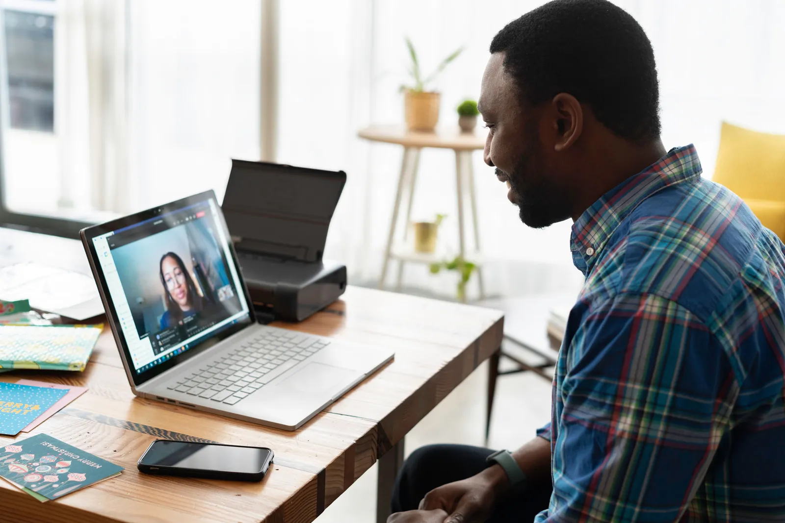 Man engaged in a video call with a colleague at a wooden desk in a modern office setting