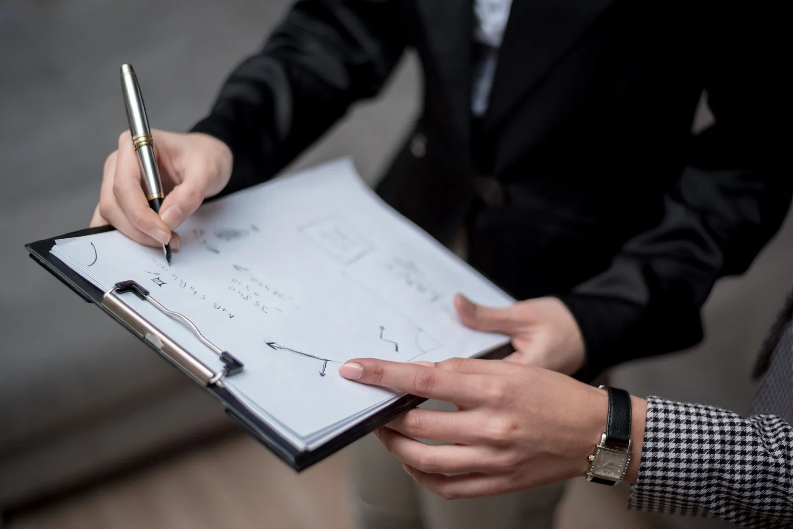 Professionals discussing notes on a clipboard during a business meeting
