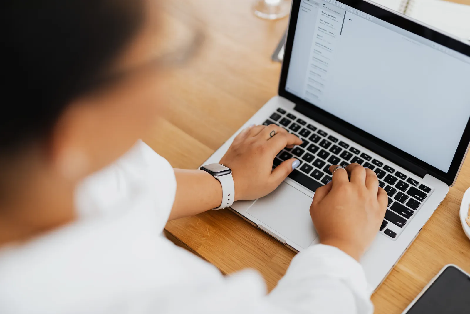 High angle shot of a person typing on a laptop, focused on hands and keyboard