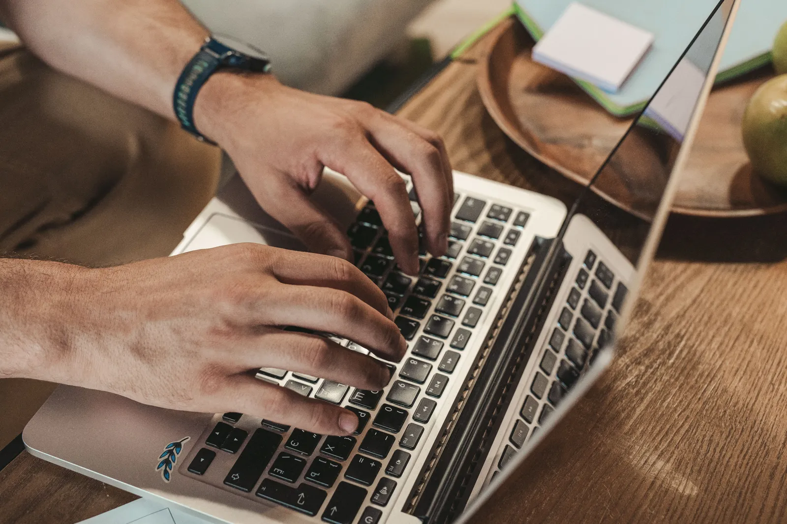 Close-up of hands typing on a laptop, capturing a productive indoor workspace vibe