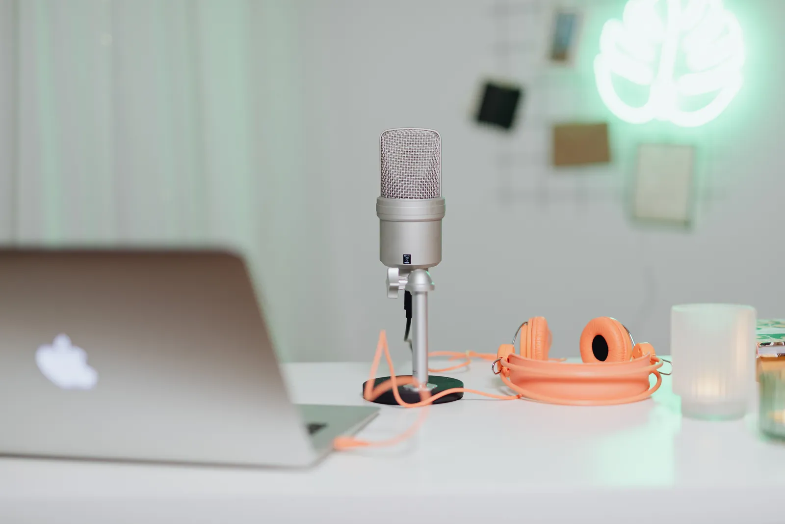 A modern desk setup featuring a condenser microphone, laptop, and headphones in a stylish workspace