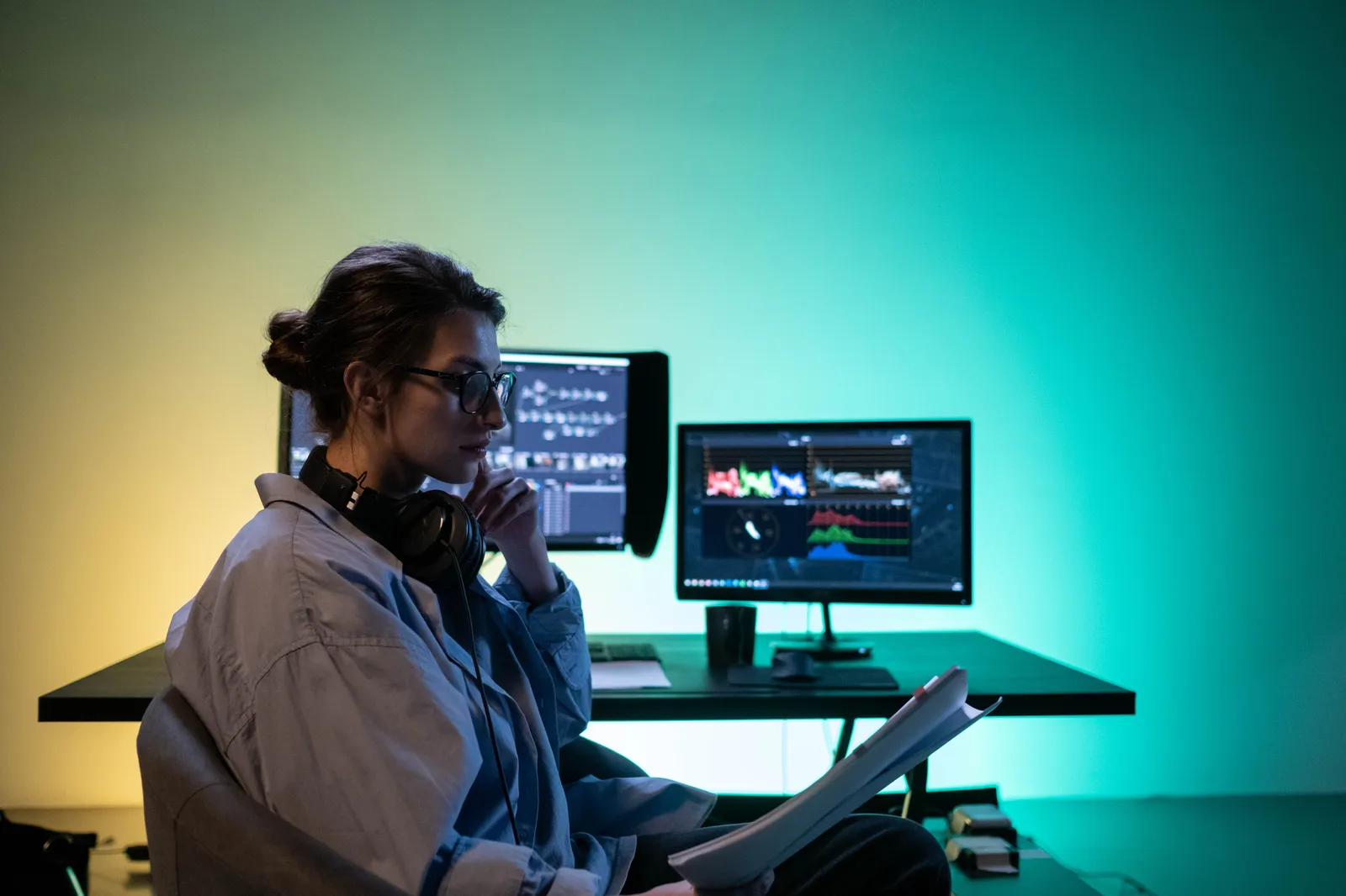 Woman editing video at modern desk setup with dual monitors in an office