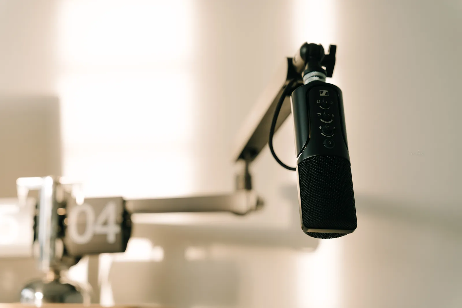 A sleek professional microphone on a boom arm in a minimalist studio