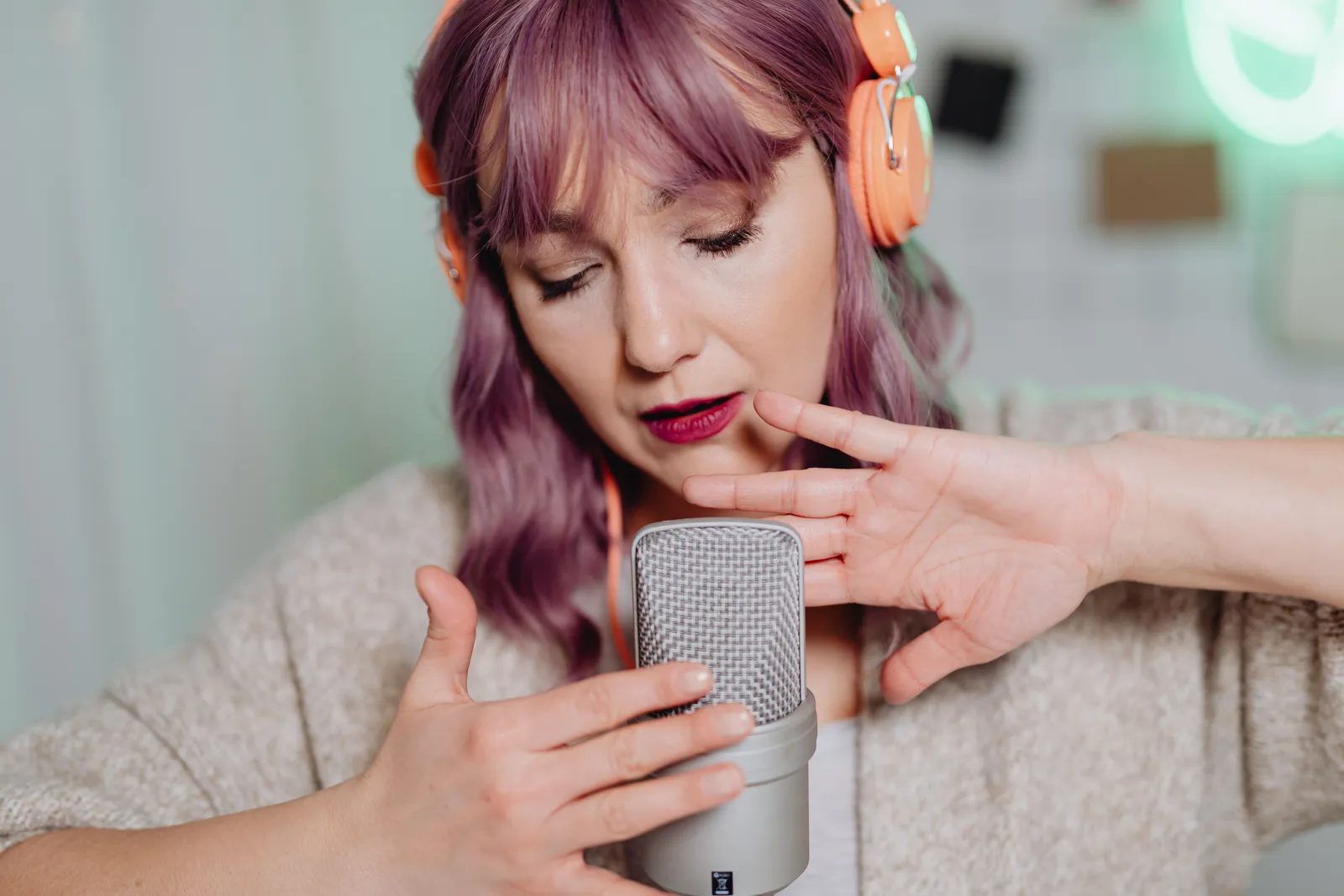 A woman in headphones creating ASMR content indoors with a professional microphone