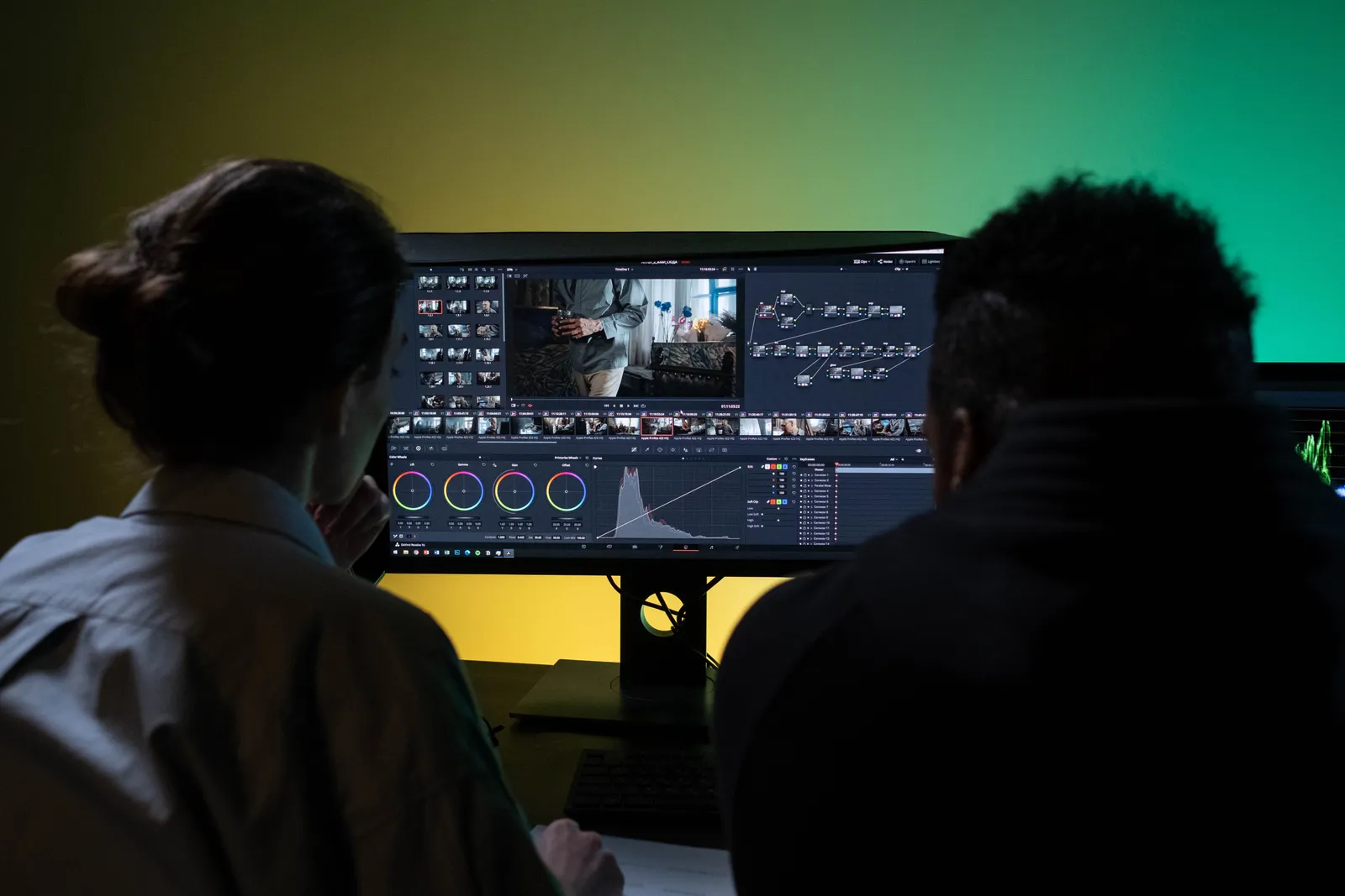 Team of two professionals video editing in a modern setup with dual monitors