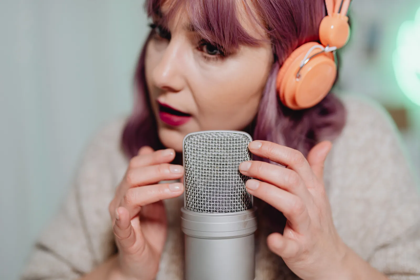 Woman recording ASMR audio with a microphone and headphones in a cozy indoor setting