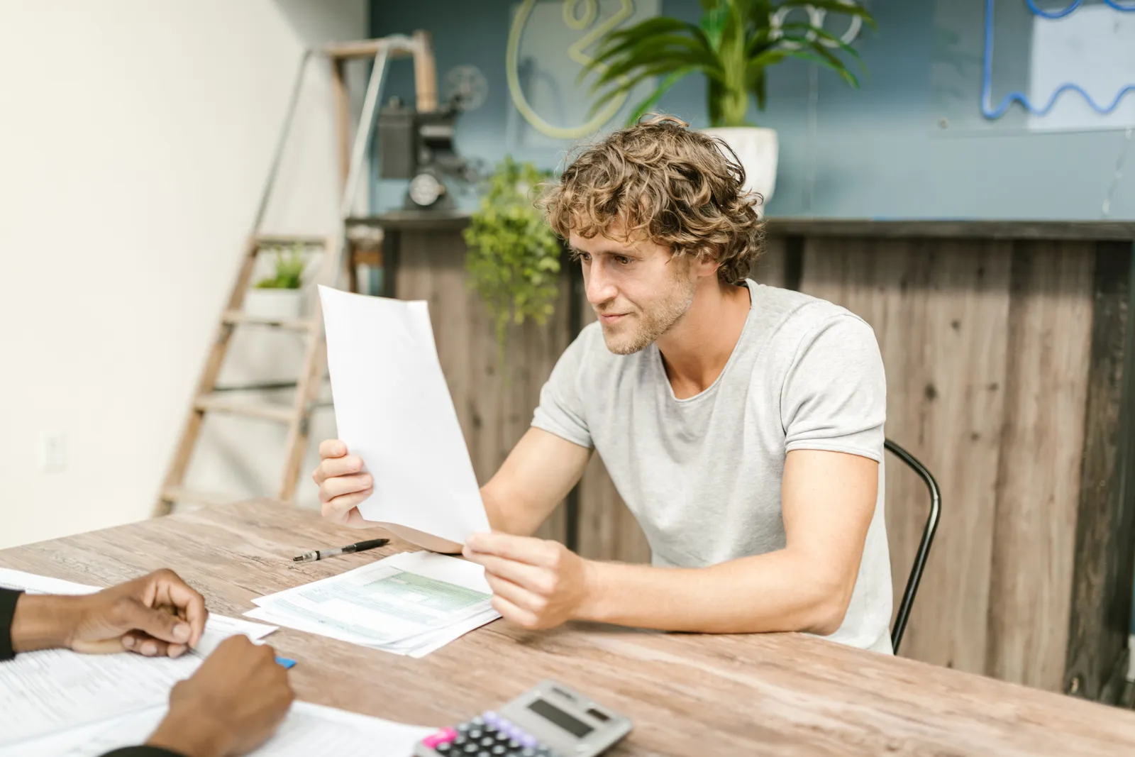 A man with curly hair evaluates documents at a desk, highlighting focused work in a professional setting