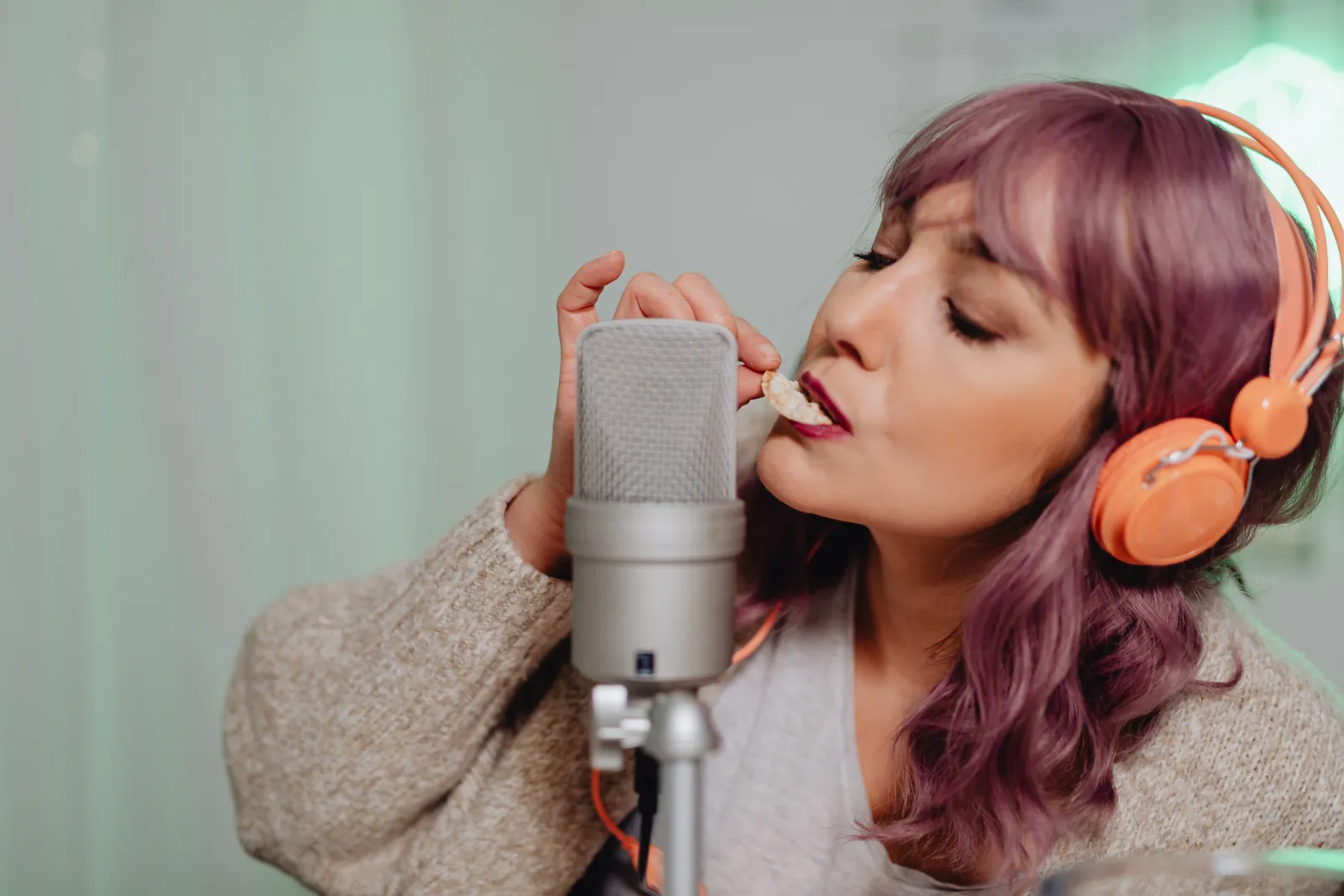Young woman recording ASMR content with a microphone and headphones indoors