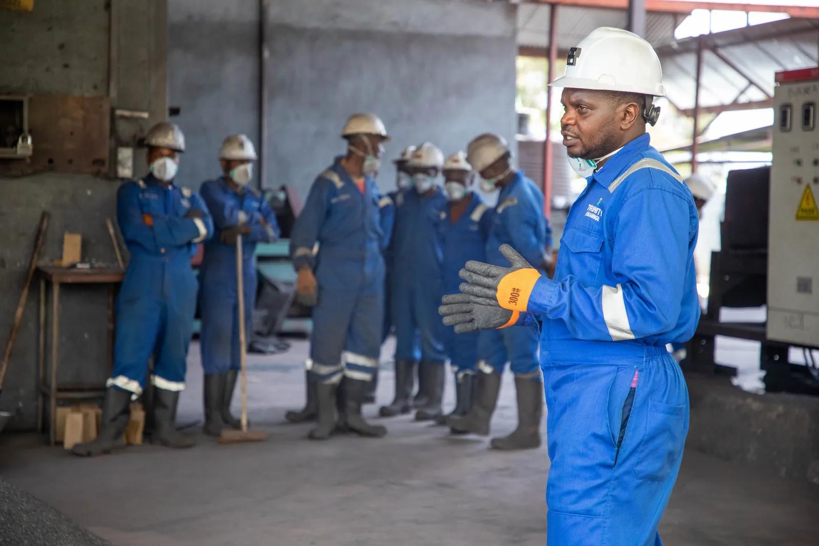 A group of factory workers in safety gear receiving training indoors