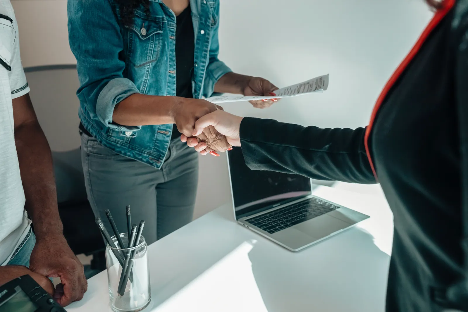 Two people shaking hands over a desk signifies a business agreement or partnership