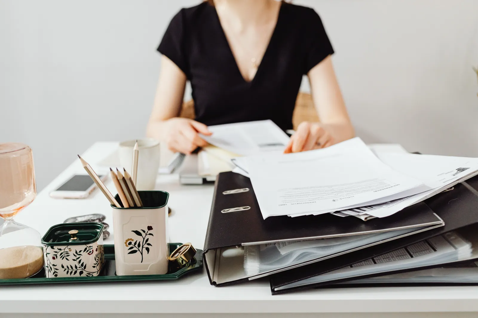 A woman at a desk working with binders and documents, featuring essential office supplies