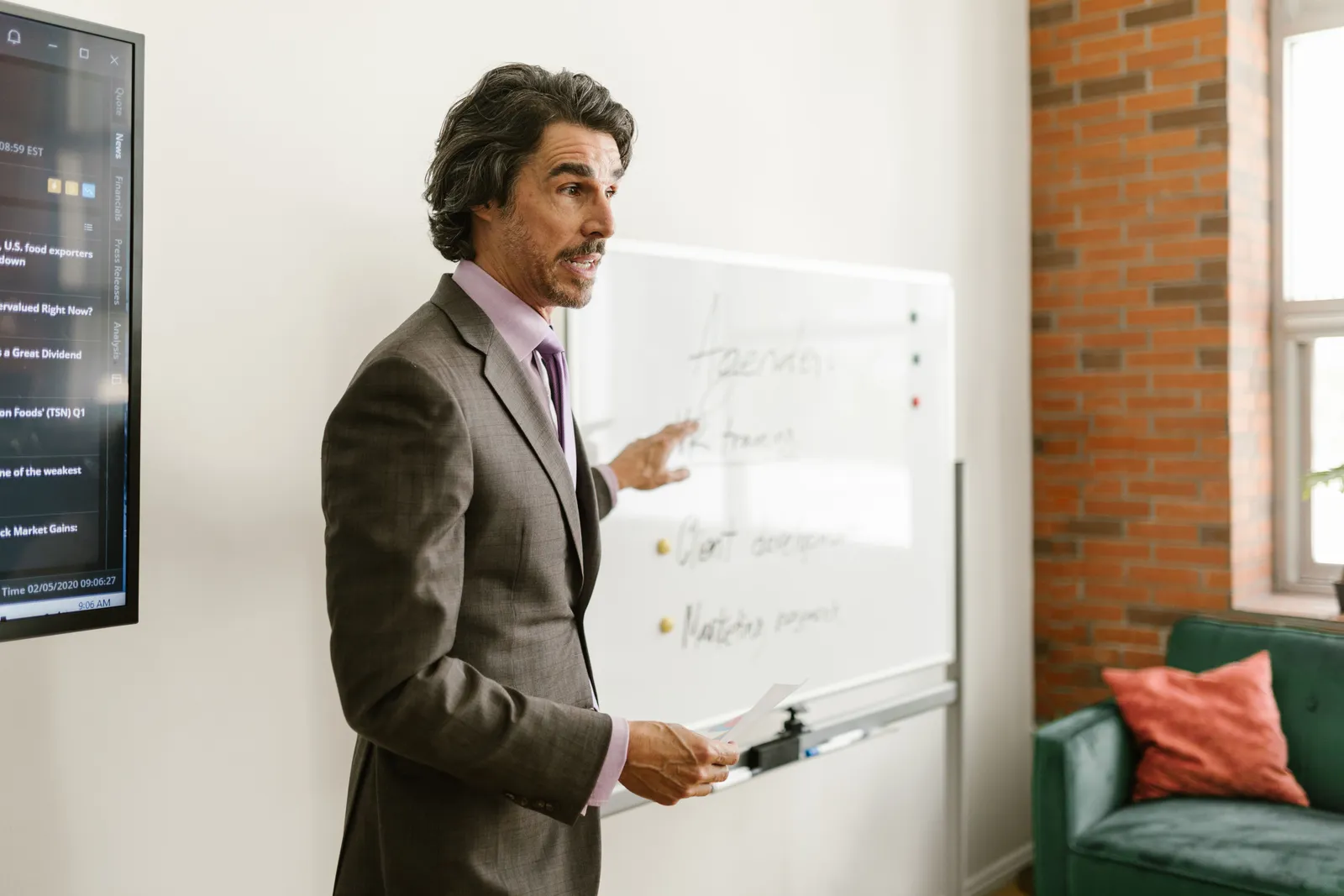 Professional businessman explaining strategy during meeting using a whiteboard in a modern office setting