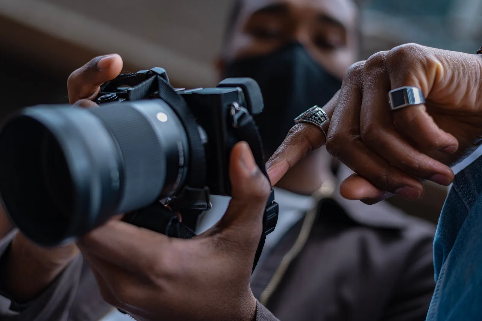 A close-up view of hands holding and adjusting a DSLR camera indoors