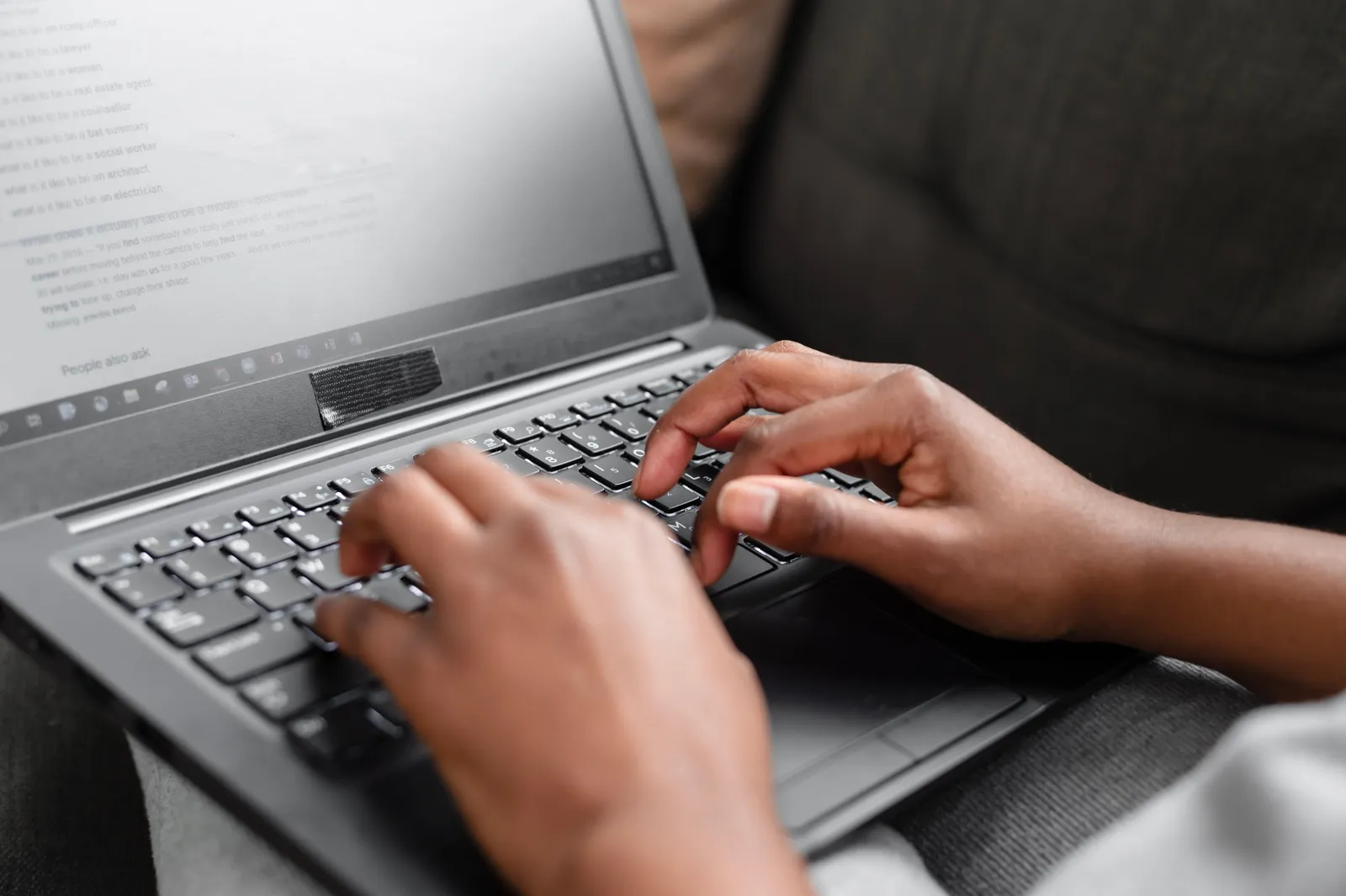 Close-up of hands typing on a laptop keyboard, working from home setting