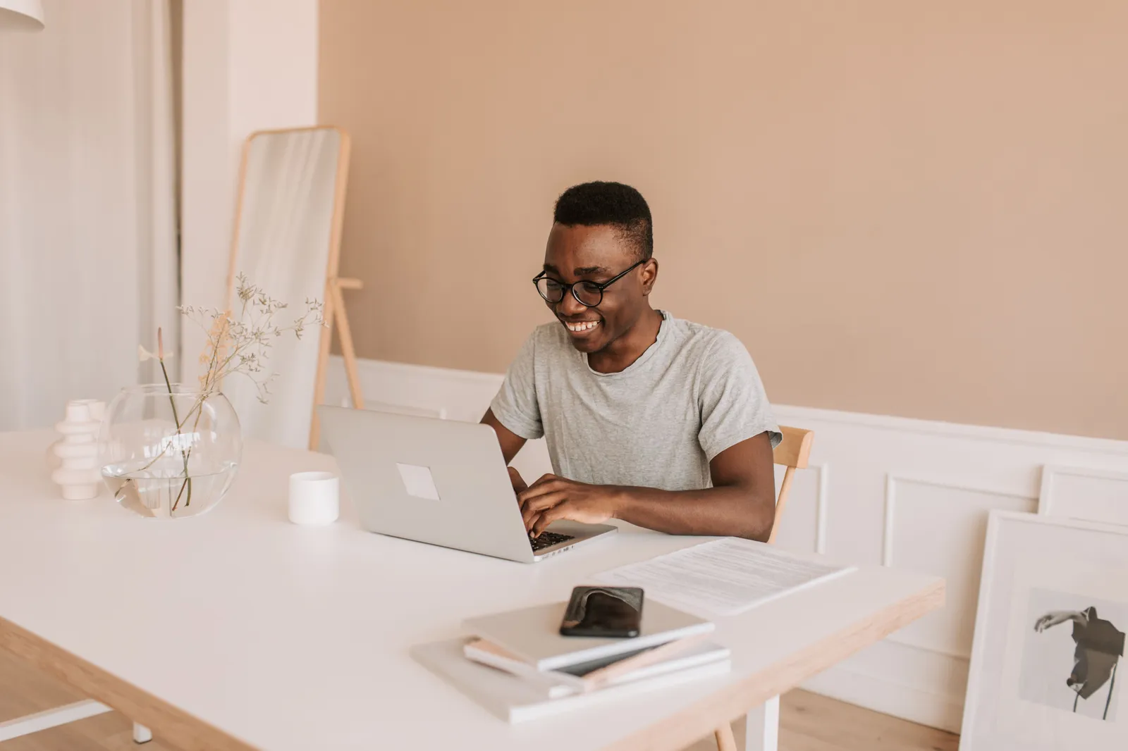 Happy young man typing on laptop in bright modern home office, enjoying his work