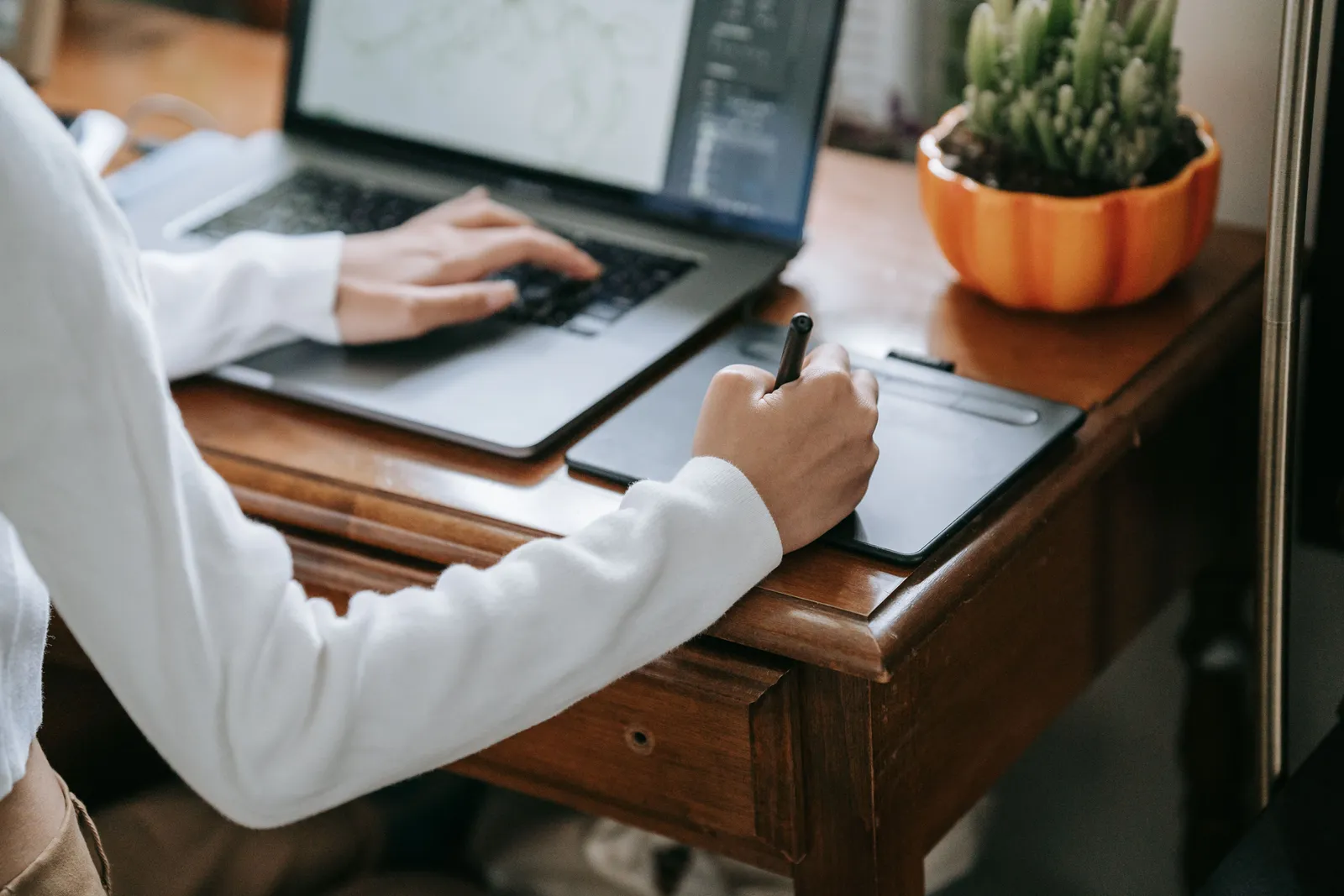 Close-up of designer working on graphics tablet with laptop, enhancing creativity and digital work