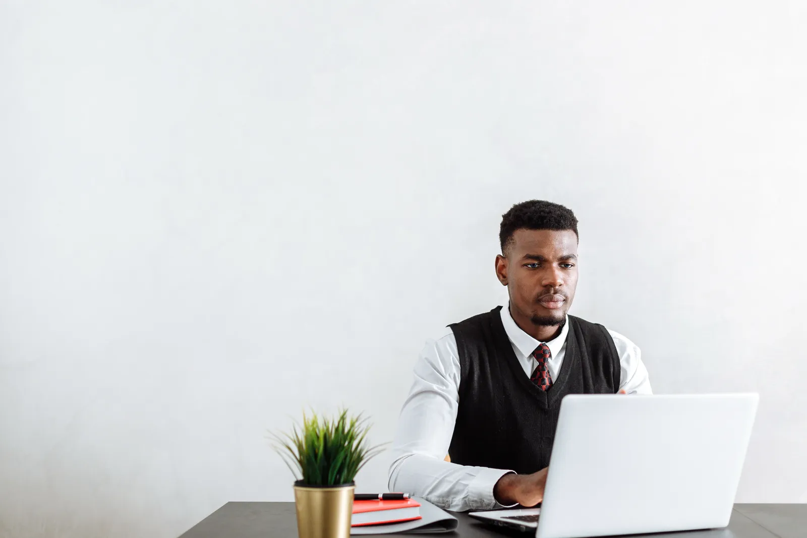 Professional man sitting at a desk working on a laptop in a modern office environment