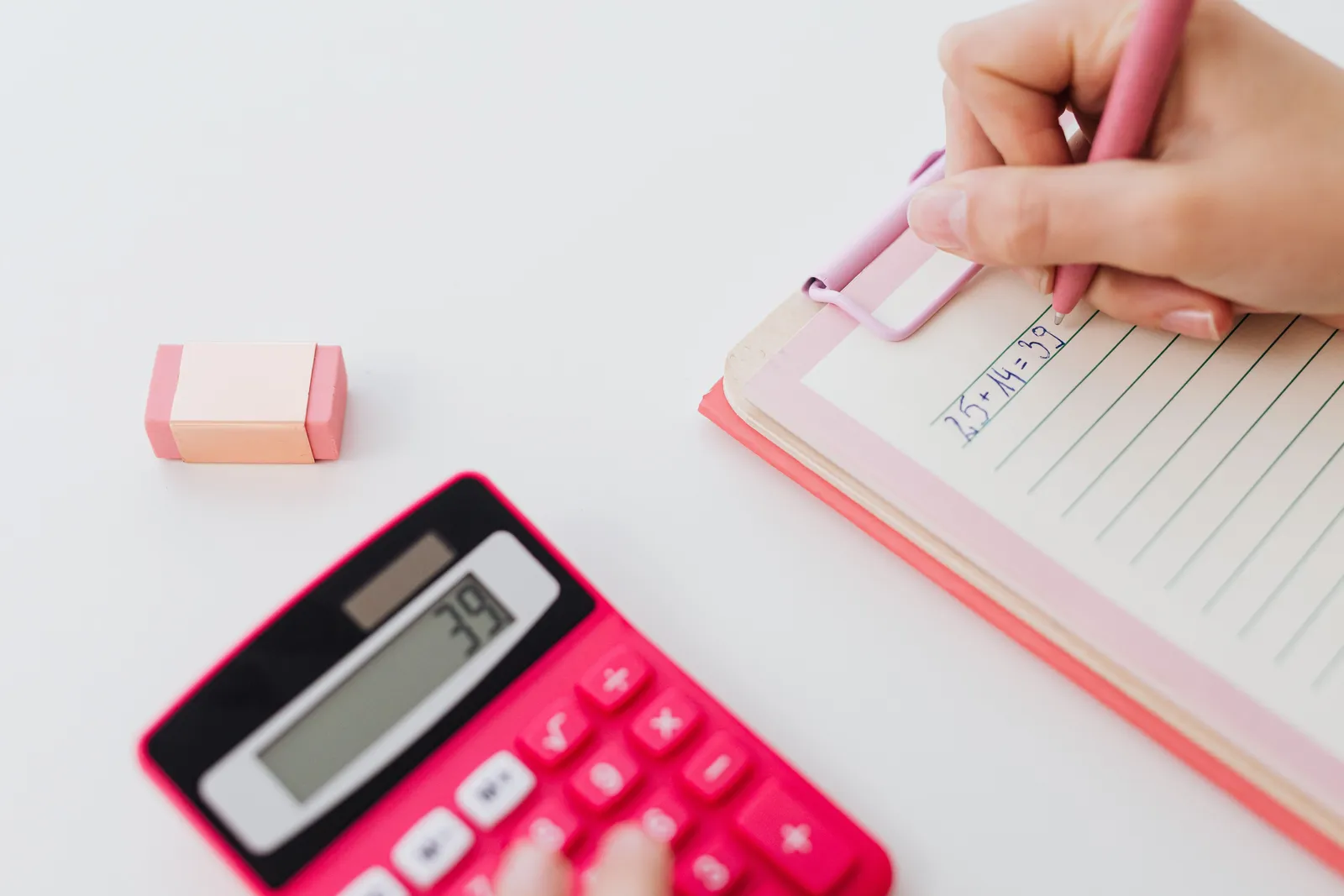 Close-up of hands using a calculator and writing equations on a notebook, perfect for math concepts